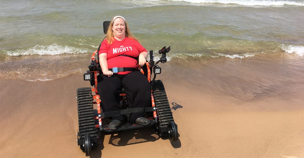 Karin Willison riding in a tank wheelchair on the beach.